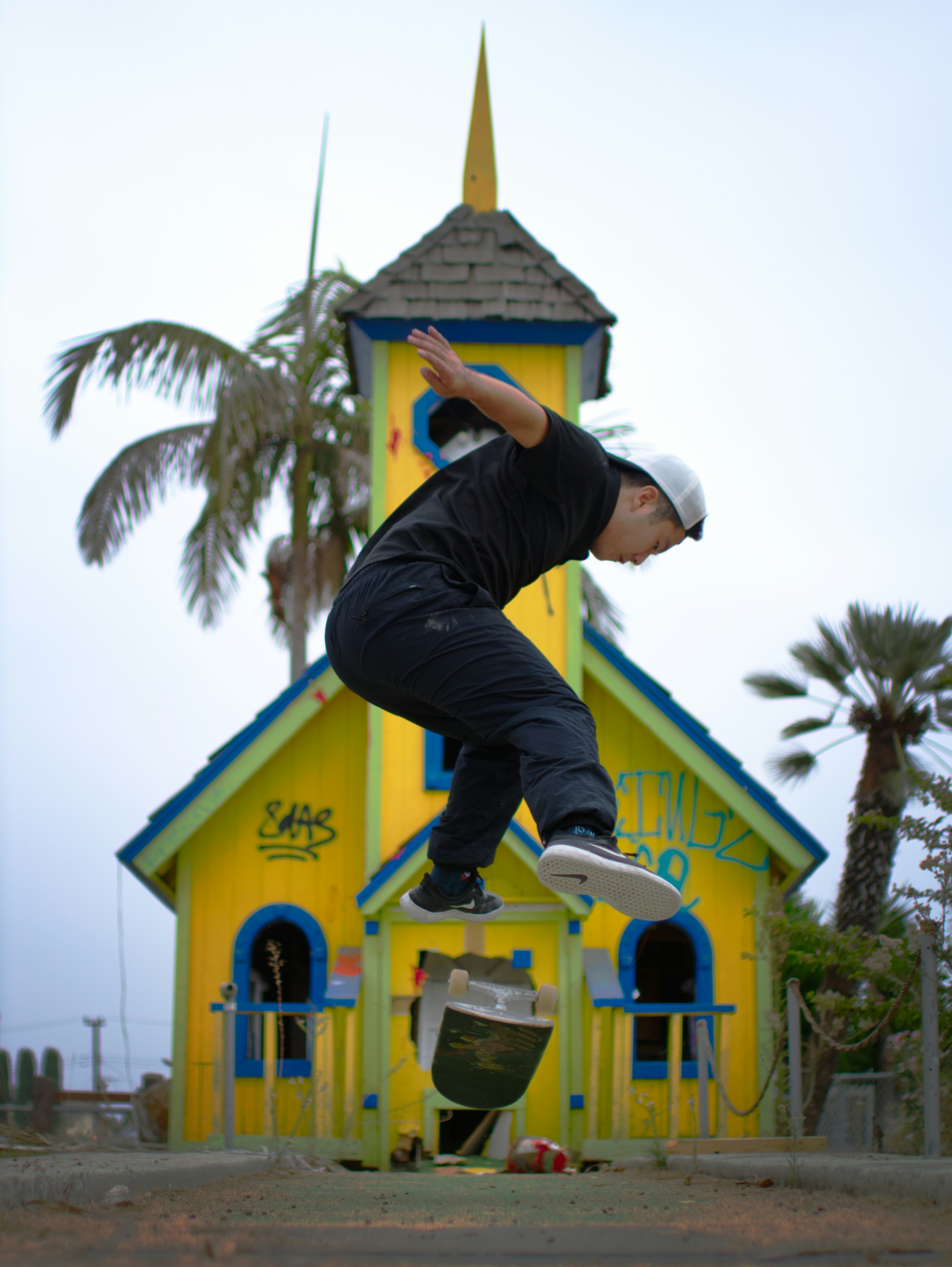 man in black jacket and blue pants jumping on blue and white wooden house during daytime