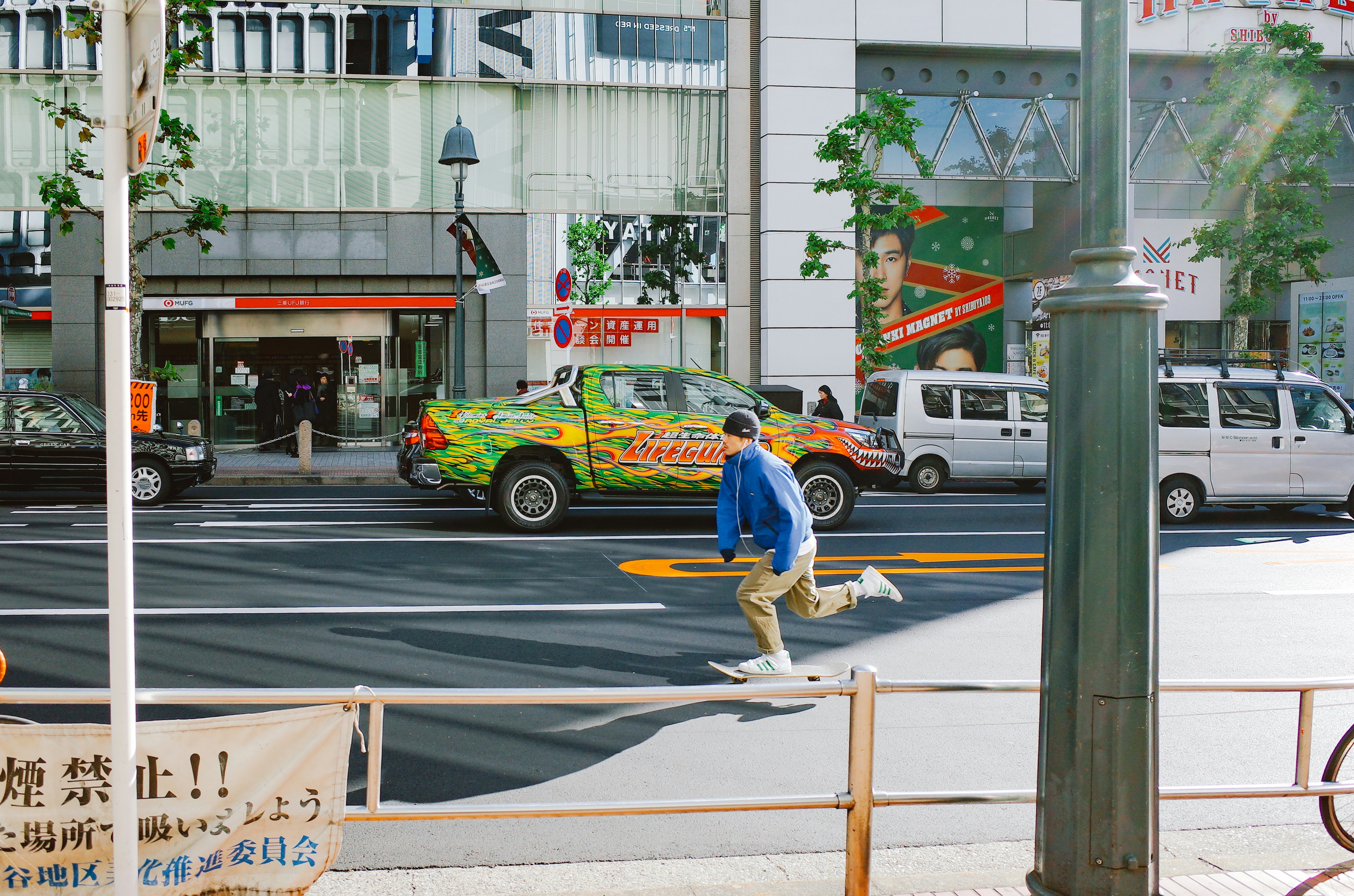 Man skateboarding down a city street with cars.